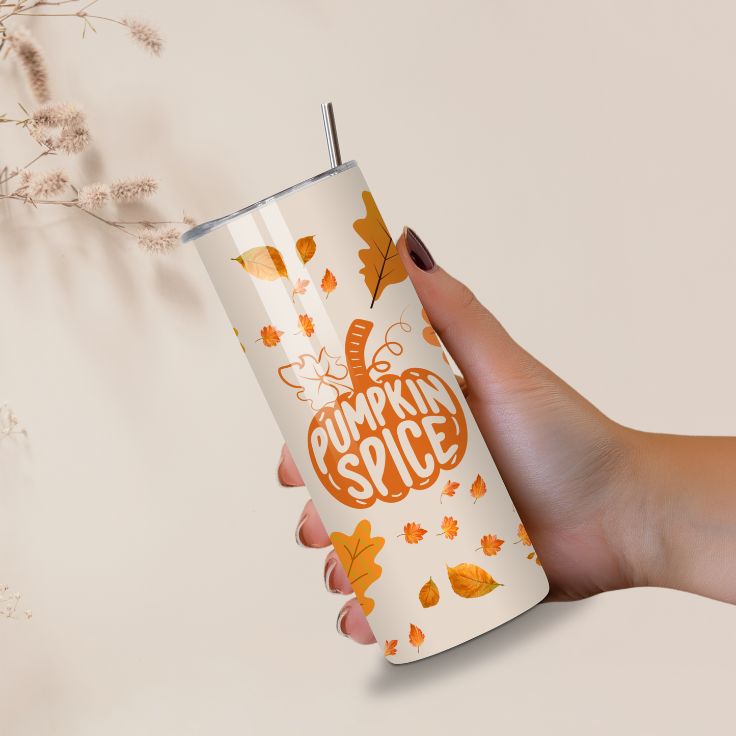 Hand holding a pumpkin spice-themed tumbler with leaf designs on a neutral background