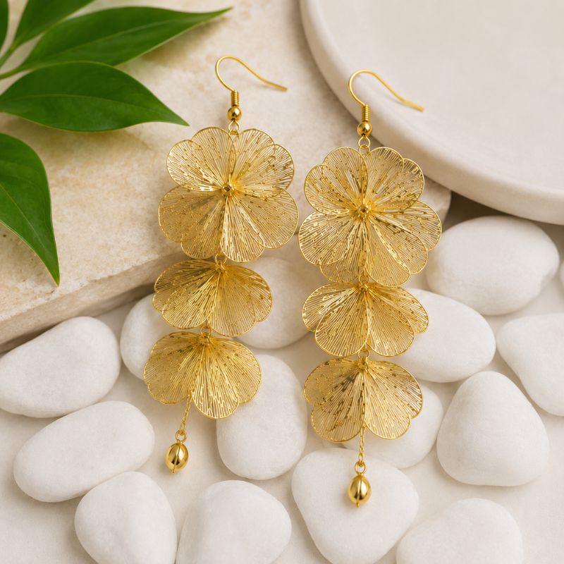 Artful Filigree Flower Drop Earrings on pebbles with green leaves