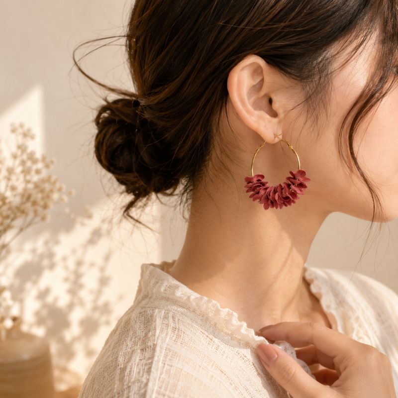Close-up of a person wearing pink floral hoop earrings with a blurred background