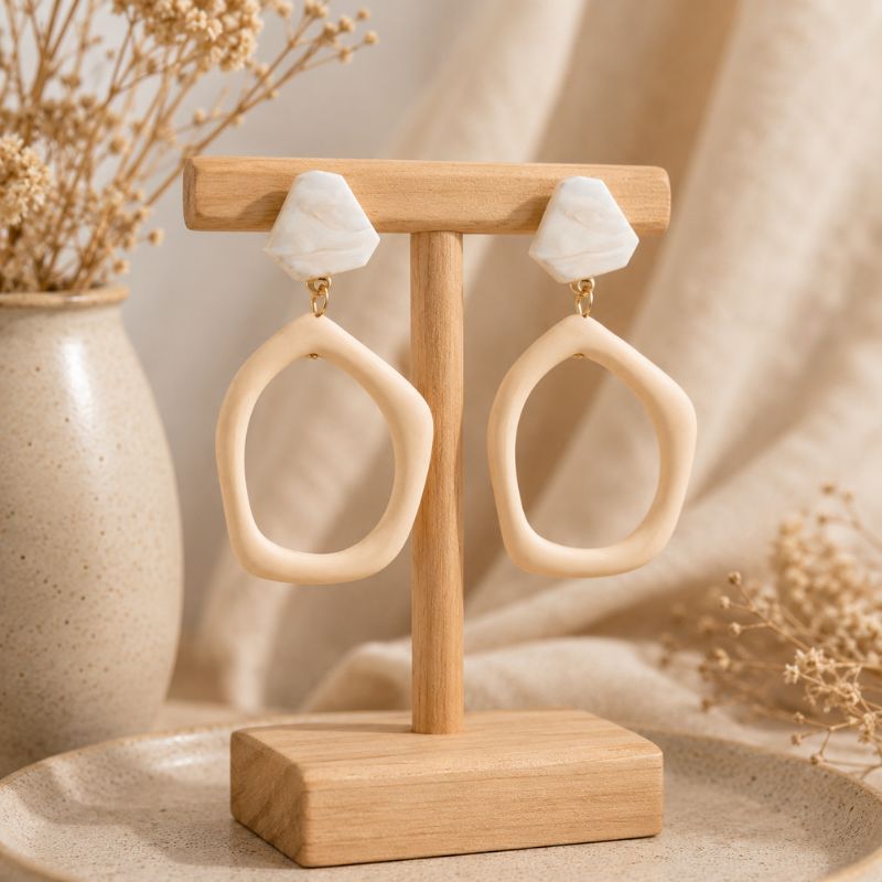 Pair of beige hoop earrings on a wooden stand with a neutral background-Designs by Berniemae