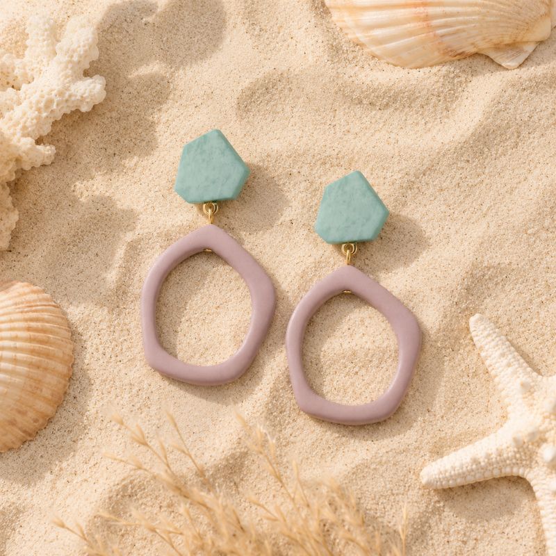 Pair of earrings with pink and green stones on a sandy background with shells and starfish.-Designs by Berniemae