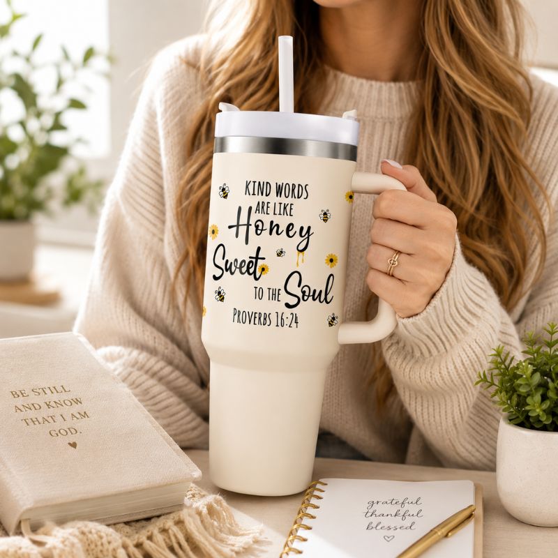 Woman holding a white tumbler with a motivational quote, surrounded by books and plants.