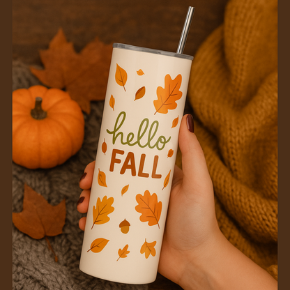 Hand holding a tumbler with 'hello Fall' and leaf design, surrounded by autumn elements.