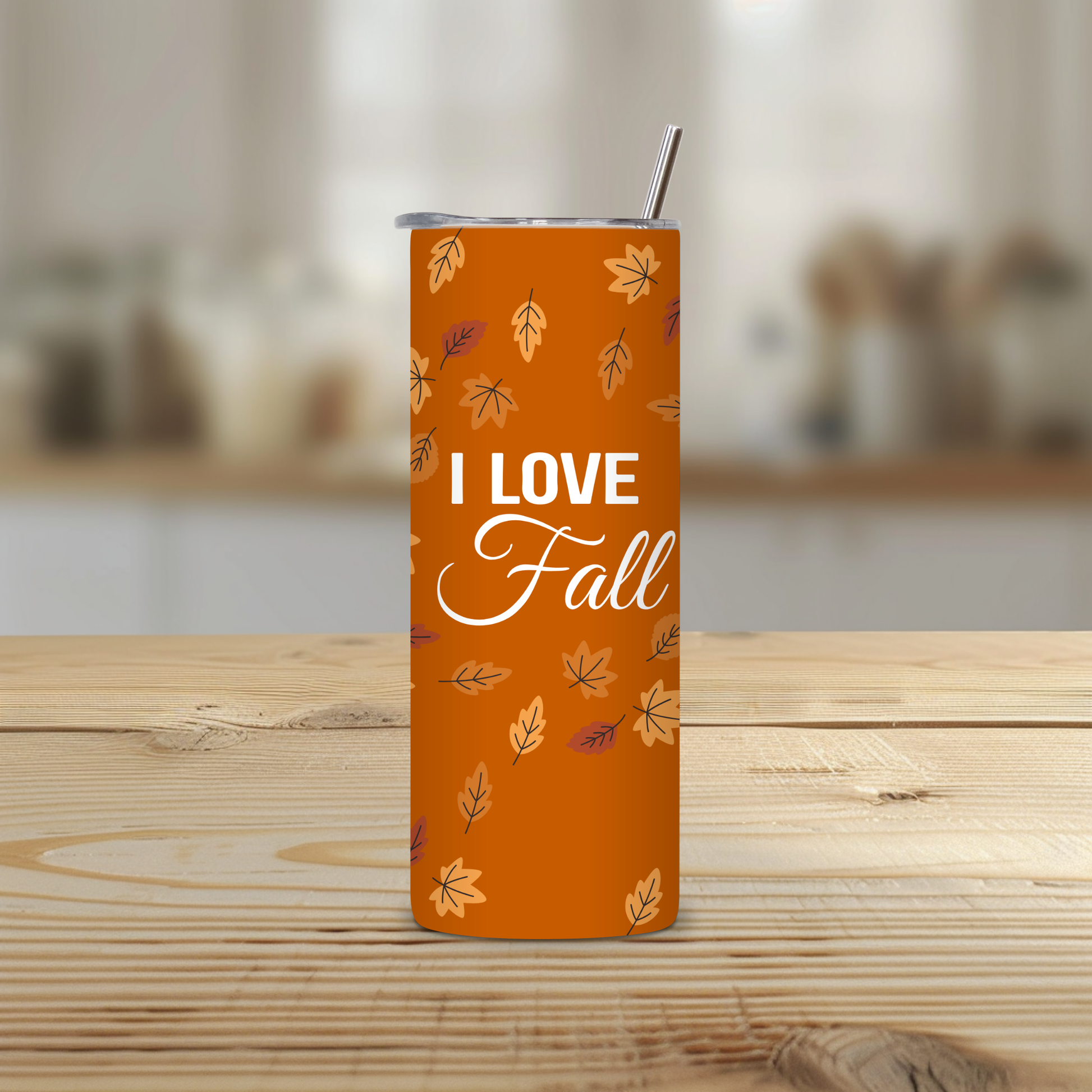 Orange tumbler with 'I Love Fall' text and leaf patterns on a wooden surface.