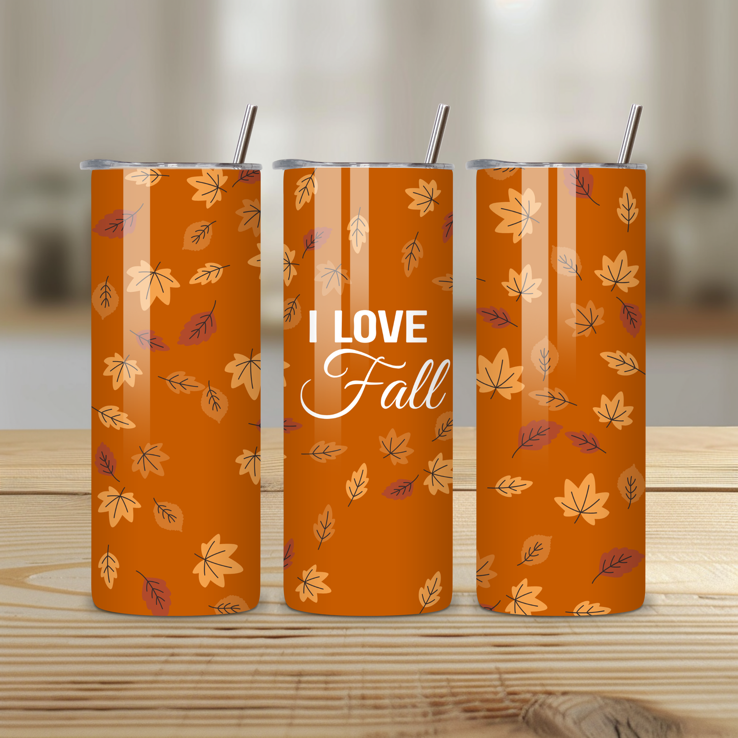 Three orange tumblers with leaf patterns and 'I Love Fall' text on a wooden surface.