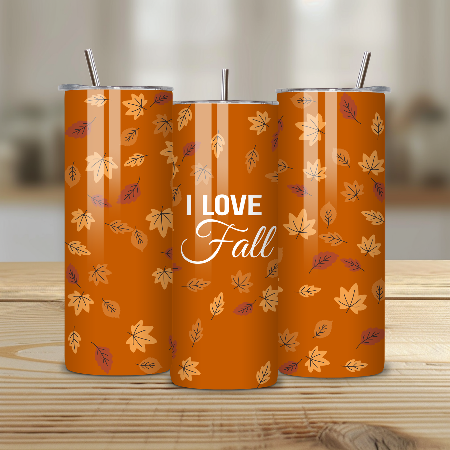Two orange tumblers with leaf pattern and 'I Love Fall' text on a wooden surface.