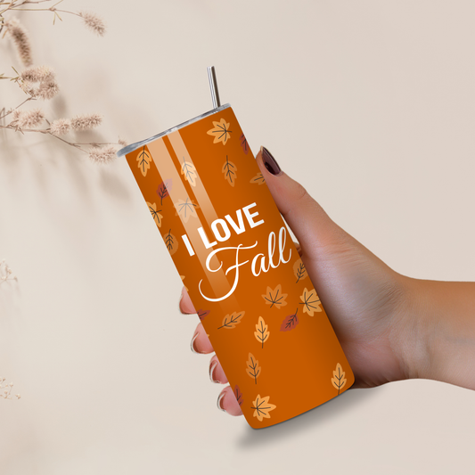 Hand holding a 'I Love Fall' insulated tumbler with autumn leaf design on a neutral background