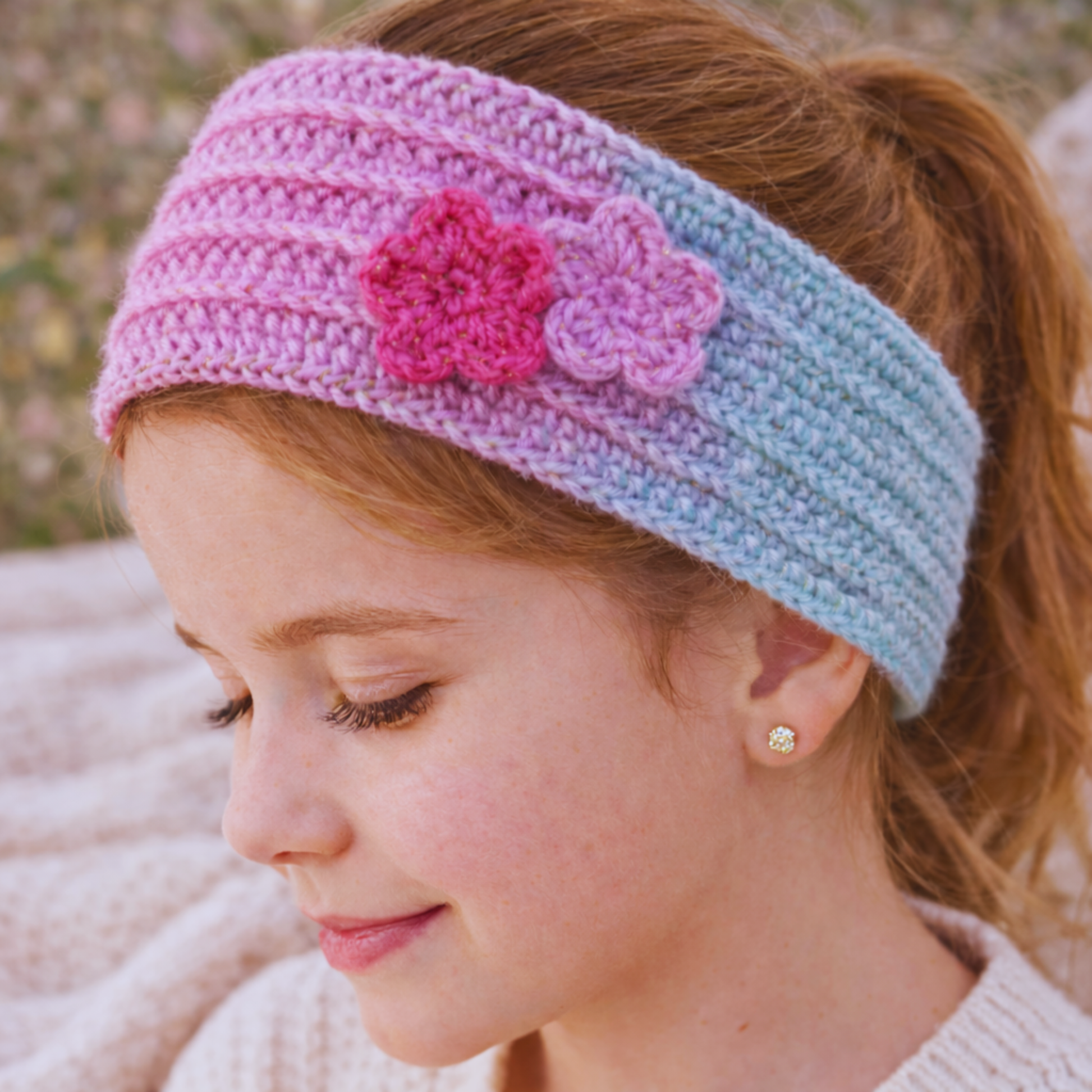 Girl wearing a colorful knitted headband with flowers in an outdoor setting