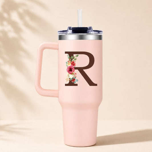 Pink tumbler with floral design and letter 'R' on a beige background