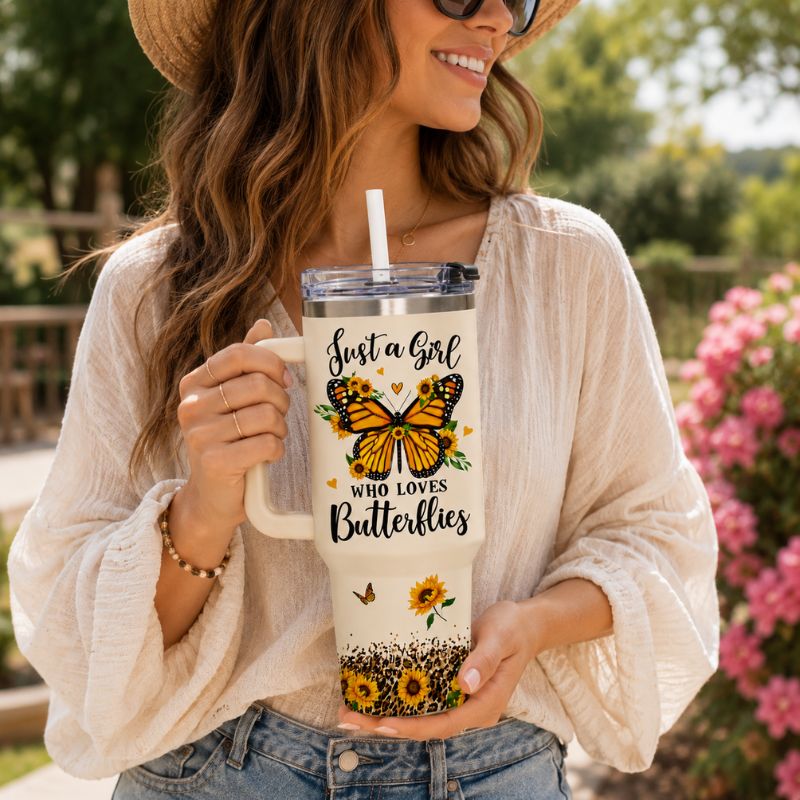 Woman holding a mug with butterfly design and text outdoors