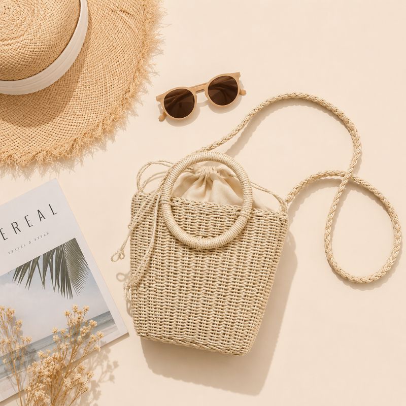 Woven handbag with sunglasses and a hat on a light background