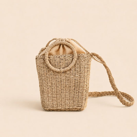 Coastal woven straw crossbody handbag with circular handles on a soft beige background